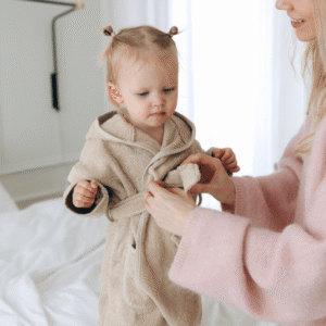 Meisje met camel kleurig badjasje, die haar moeder met de band dicht knoopt